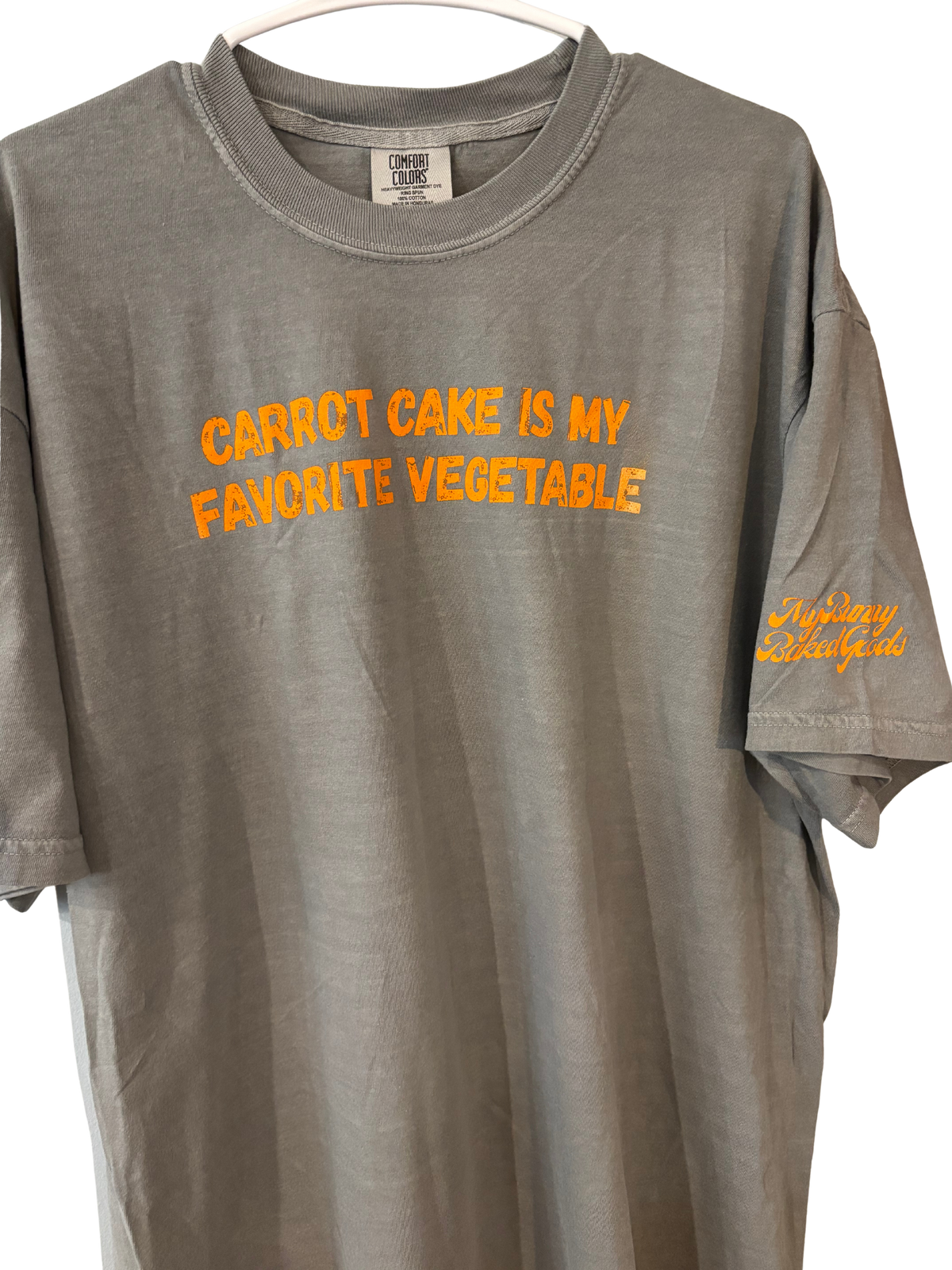 Gray Carrot Cake Tee on a hanger with orange lettering and sleeve logo